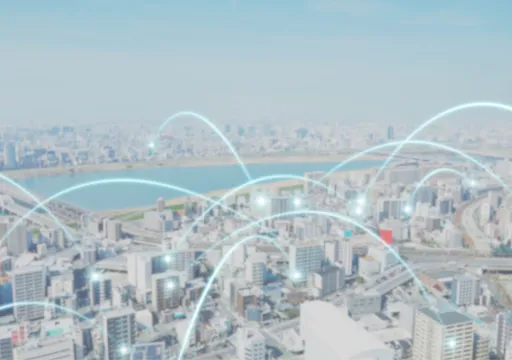 Aerial view of a city overlaid with glowing teal arcs that connect buildings across the network.